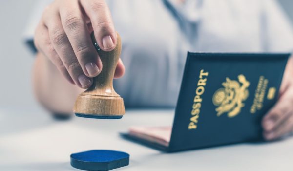 A woman is using a rubber stamp to process an Express Entry passport.